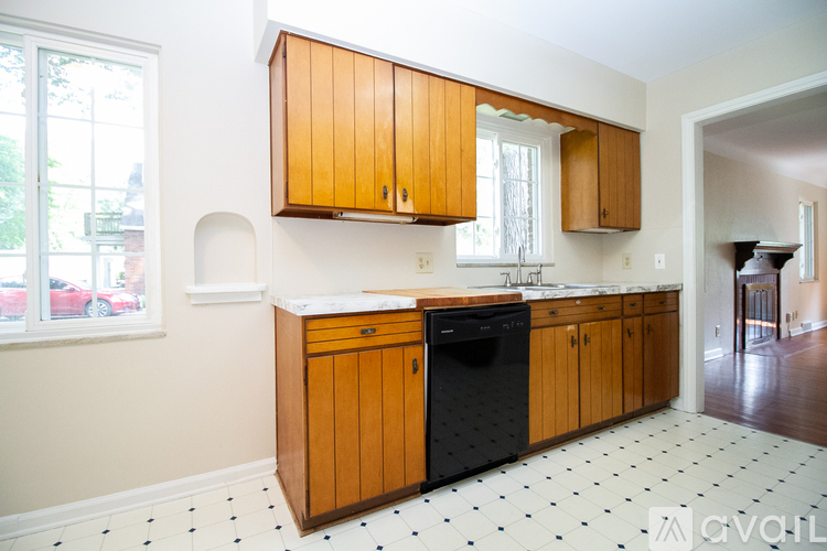A kitchen with wooden cabinets and a black dishwasher.
