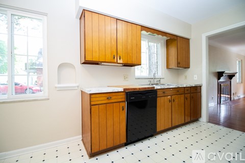 A kitchen with wooden cabinets and a black dishwasher.