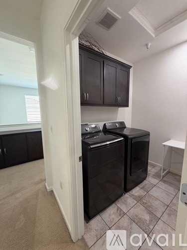 A black dishwasher is in a kitchen with a white wall and black cabinets.