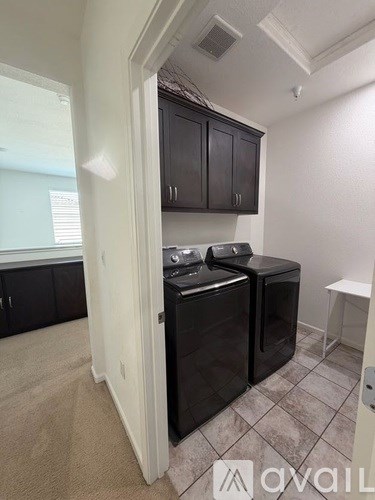 A black dishwasher is in a kitchen with a white wall and black cabinets.