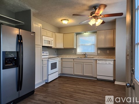 A kitchen with a refrigerator, microwave, oven, and sink.