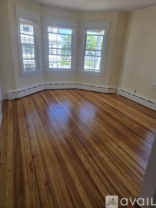 A room with wooden floors and three windows.