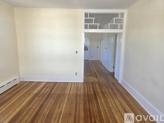 A room with wooden flooring and white walls.