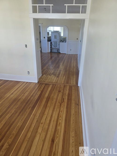 A hallway with wooden floors and white walls.