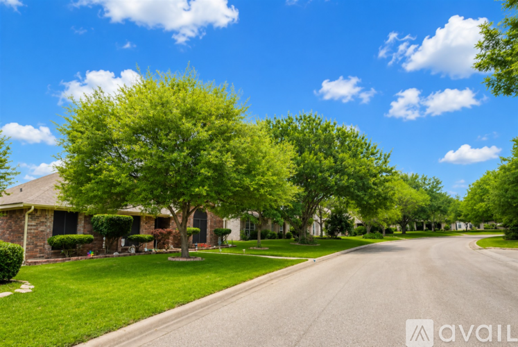 A tree-lined street with a house on the left.