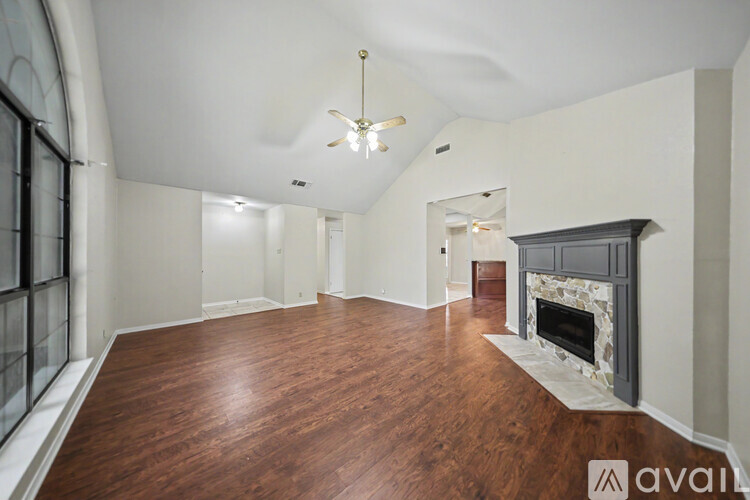 A spacious living room with wood flooring and a fireplace.