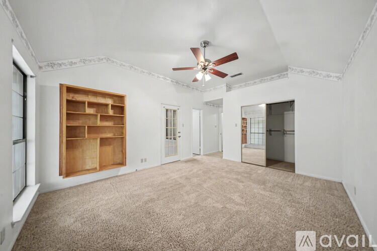 A spacious room with wooden floors and a ceiling fan.