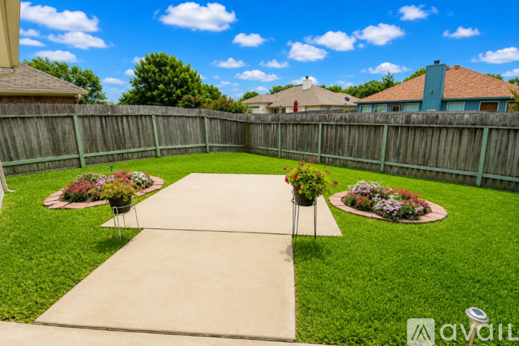 A backyard with a concrete walkway and two flowerbeds.