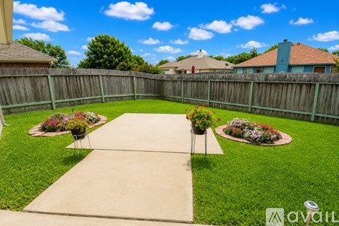 A backyard with a concrete walkway and two flowerbeds.