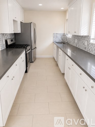 A kitchen with white cabinets and a black counter top.