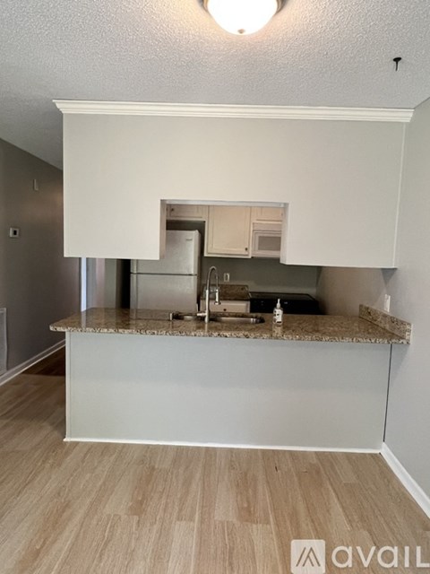 A kitchen with a granite countertop and a fridge.