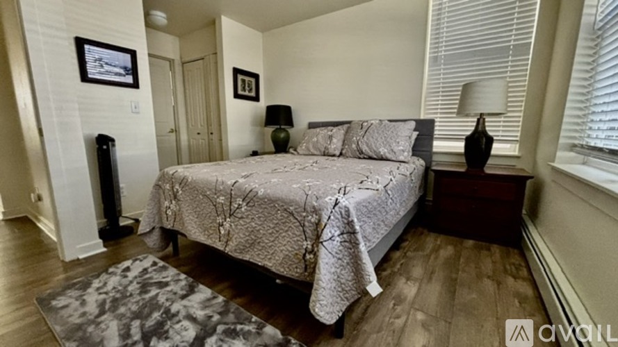 A bedroom with a large bed and a rug in the foreground.