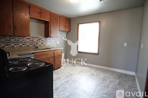 A kitchen with a black stove top oven and wooden cabinets.