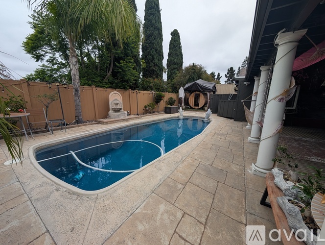 A swimming pool surrounded by a patio and a fence.