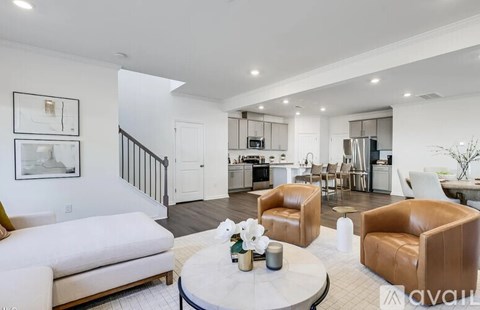 A modern living room with a white couch, brown leather chairs, and a coffee table with flowers on it.