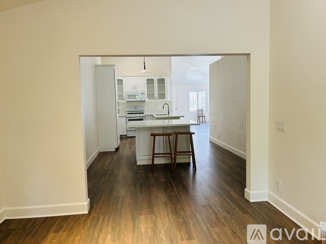 A kitchen with white cabinets and a wooden floor.
