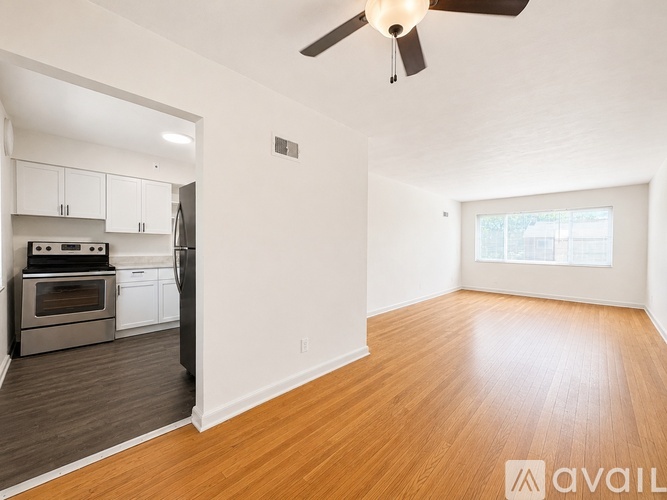 A room with a ceiling fan and a kitchen area with stainless steel appliances.