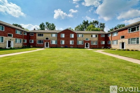 A grassy area in front of apartment buildings with a clear sky above.
