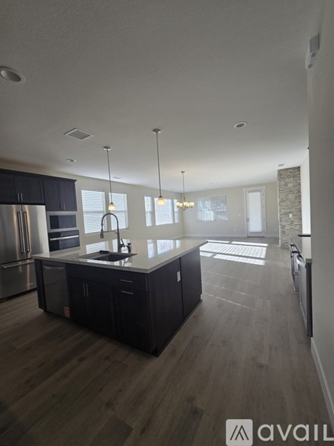 A modern kitchen with dark wood floors and stainless steel appliances.