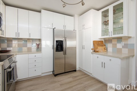 A kitchen with white cabinets and a stainless steel refrigerator.