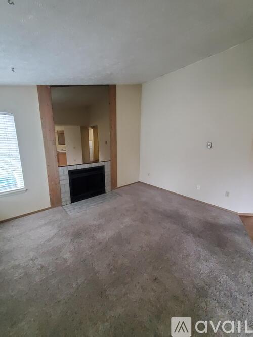 A living room with a fireplace and a large empty space.