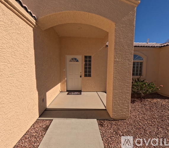 A house entrance with a white door and a gravel path leading to it.