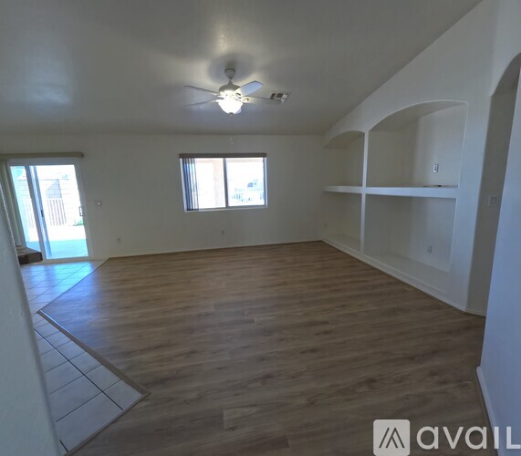 A spacious room with wooden flooring and a ceiling fan.