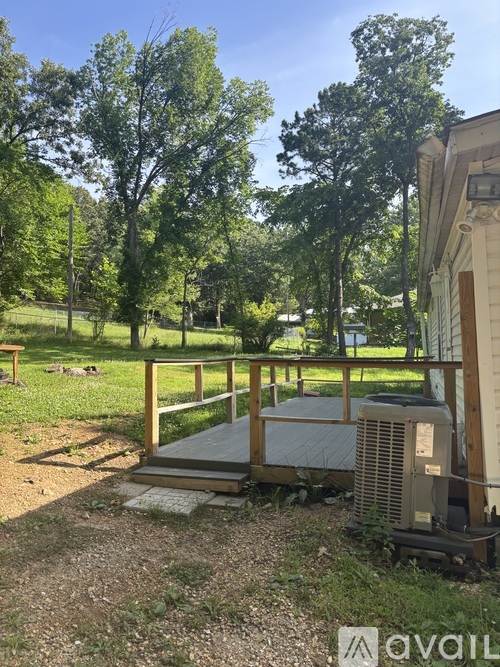A backyard with a wooden deck and a tree.