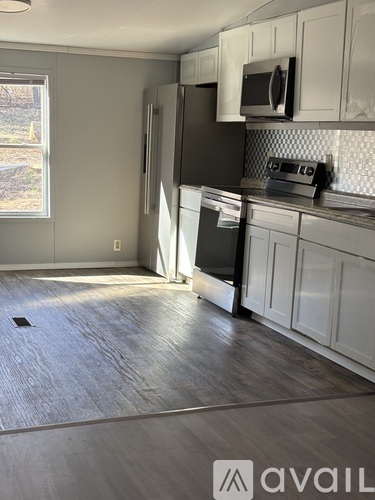 A kitchen with white cabinets and a black fridge.