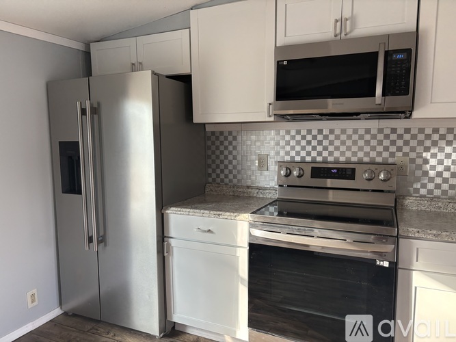 A kitchen with a stainless steel refrigerator, microwave, and oven.