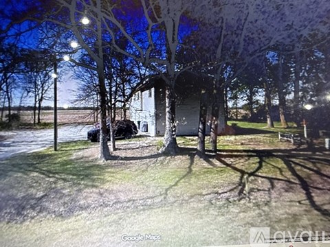 A tree-lined street with a house and a car parked in front.
