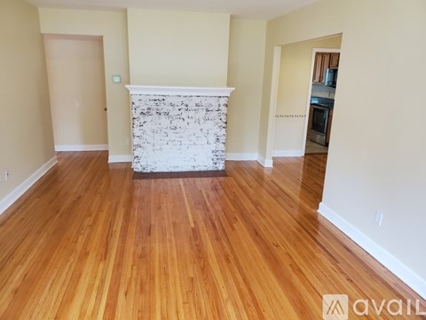 A room with wooden floors and a white fireplace.