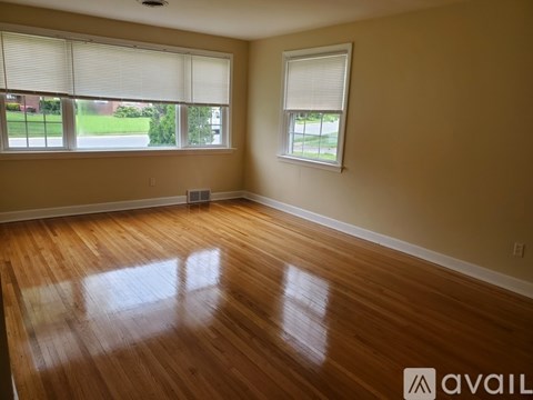 A room with wooden floors and two windows.
