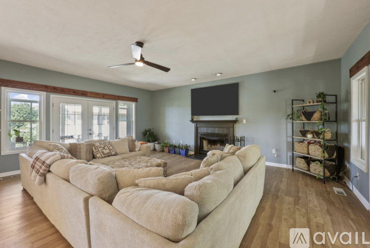 A living room with a large beige couch and a flat screen TV mounted above a fireplace.