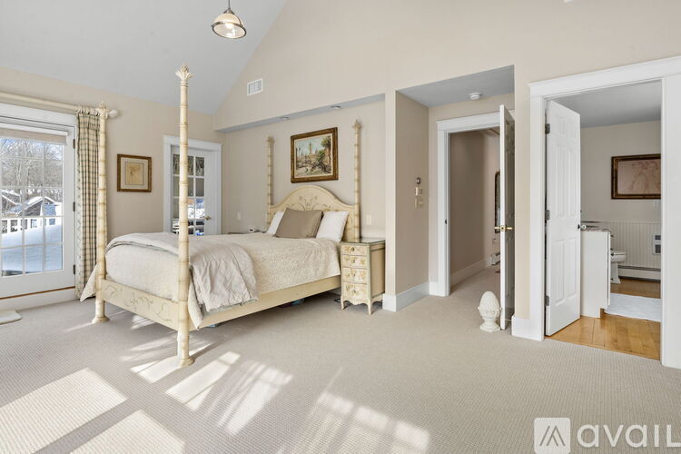 A bedroom with a four poster bed and a window with curtains.