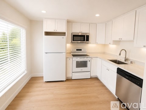 A kitchen with white cabinets and appliances.
