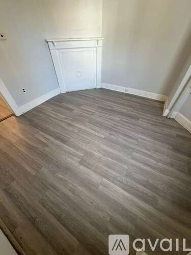 A room with a wooden floor and a white wall.