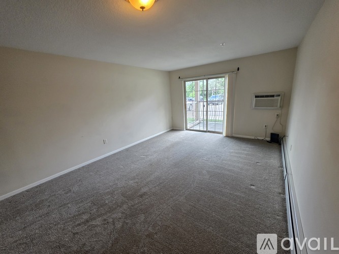 A room with a carpeted floor and a window with blinds.