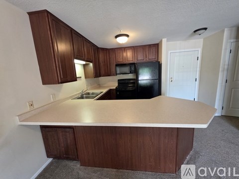 A kitchen with brown cabinets and a black fridge.