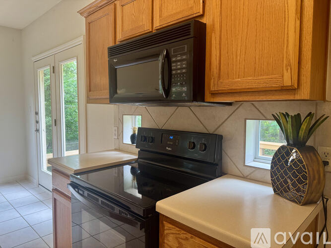 A kitchen with wooden cabinets and a black microwave above the stove.