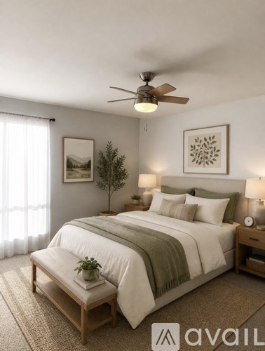 A bedroom with a large bed, a ceiling fan, and a small tree on the bedside table.