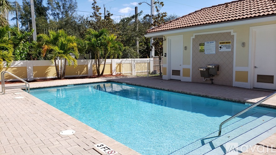 A pool with a red tile roof and a white fence.