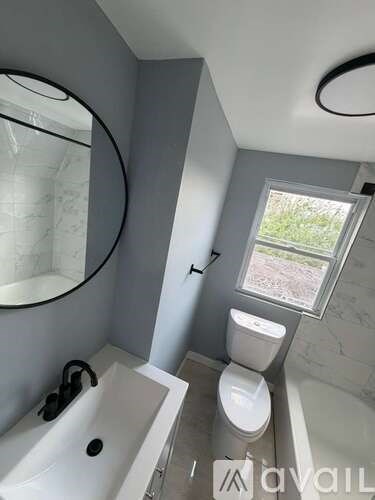 A bathroom with a toilet, sink, and mirror.