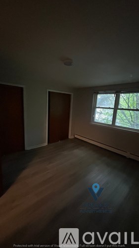 A room with wooden flooring and a window showing trees outside.