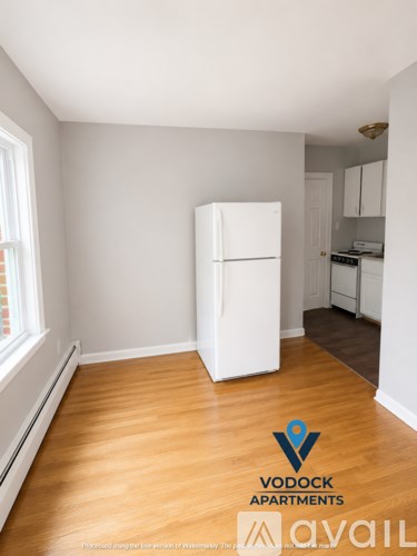 A white refrigerator in a room with wooden floors and a window.
