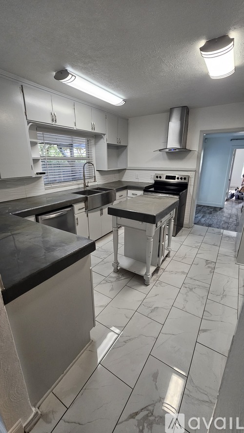 A kitchen with white cabinets and a black counter top.