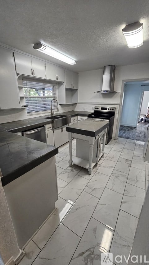 A kitchen with white cabinets and a black counter top.