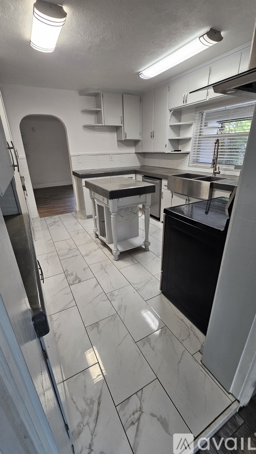 A kitchen with white cabinets and black countertops.