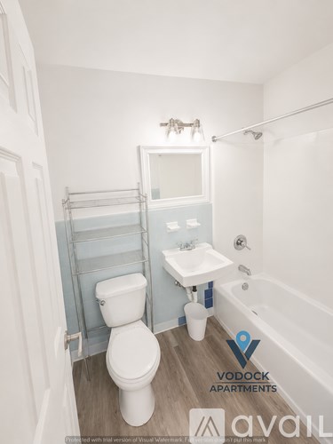 A white toilet is in a small bathroom with a white sink and a white bathtub.