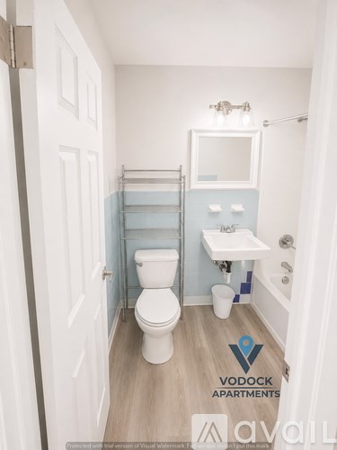 A white toilet in a small bathroom with a white sink and a mirror.